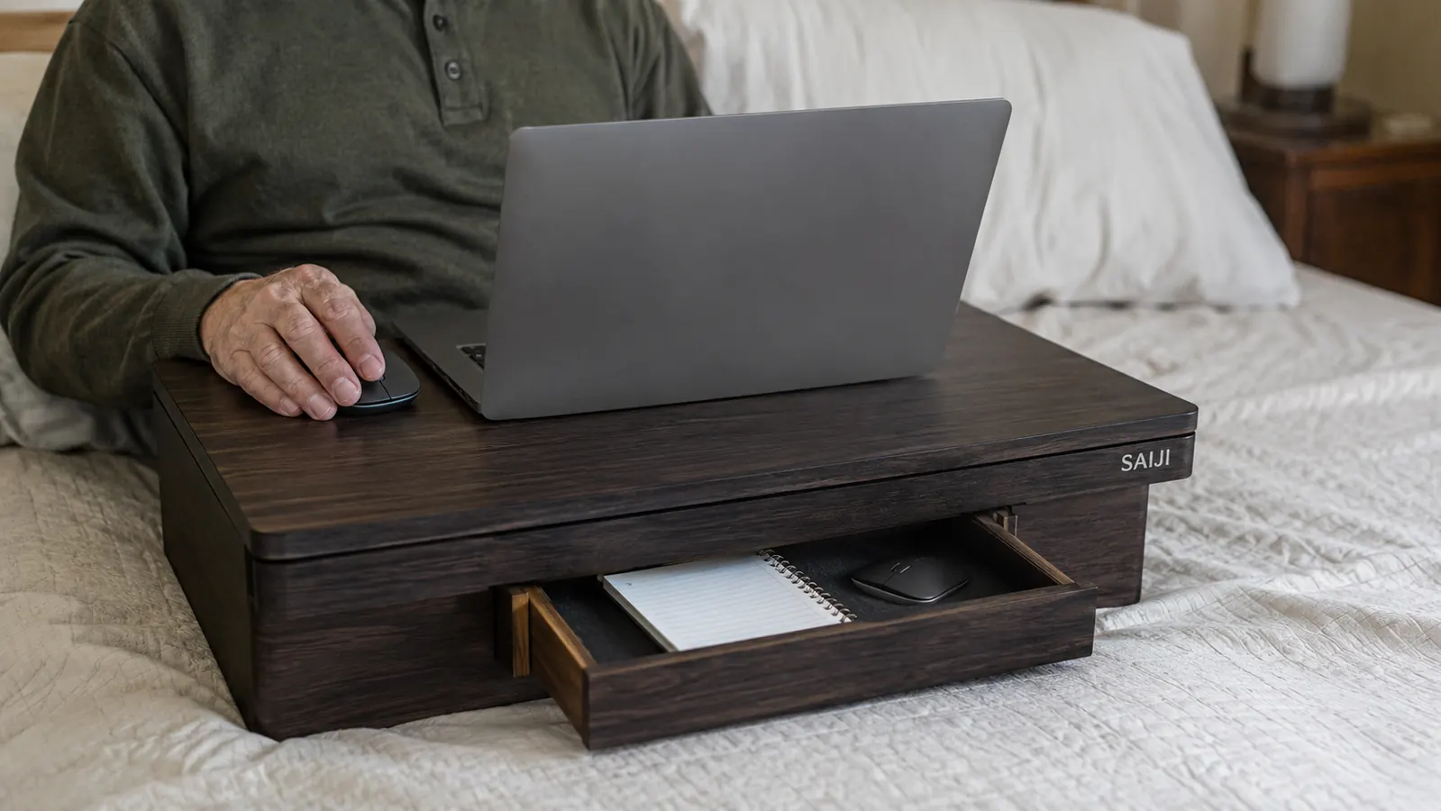 A wooden lap desk with a small storage drawer partly open showing a mouse and notepad tucked inside